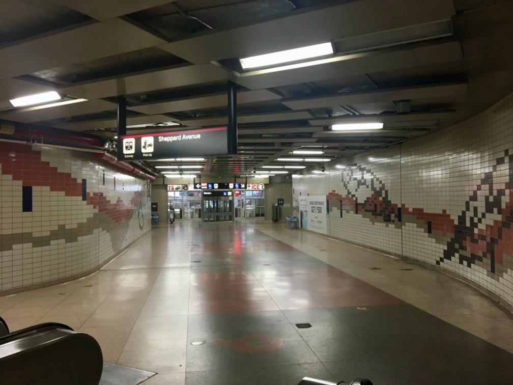 Looking back at the elevator to the subway. EXIT sign in foreground, subway sign and elevator in background.